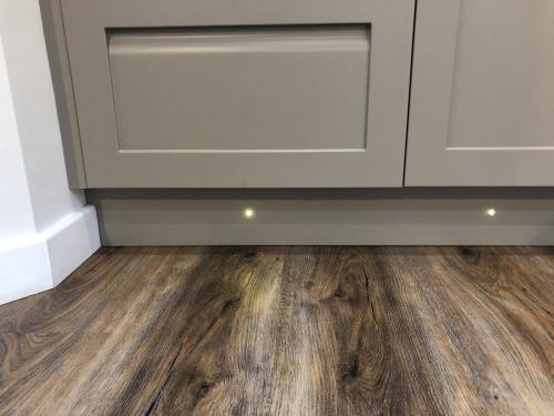 Image Of Spot Halogen Lights Under Grey Kitchen Cabinets / Cupboards, Floor Lighting In Interior Design Of Under Cabinet LED Lighting Kit And Kitchen Plinth Lights On Kickboards For Illumination Of Oak Wooden Floorboards Vinyl Flooring By Cooker Stove